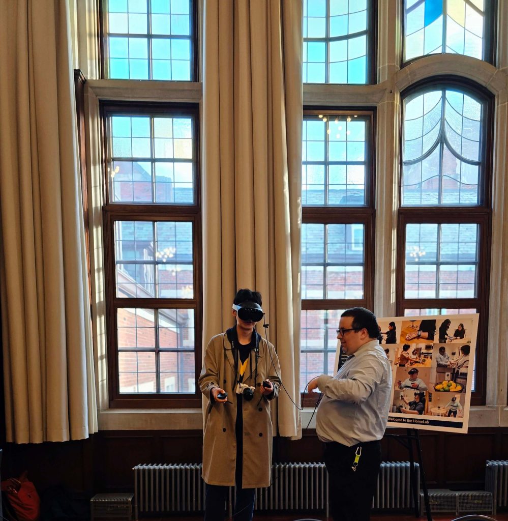 HomeLab staff member Brandon Labbree helps an attendee demonstrate the VR system at the ISR 75th Anniversary Showcase
